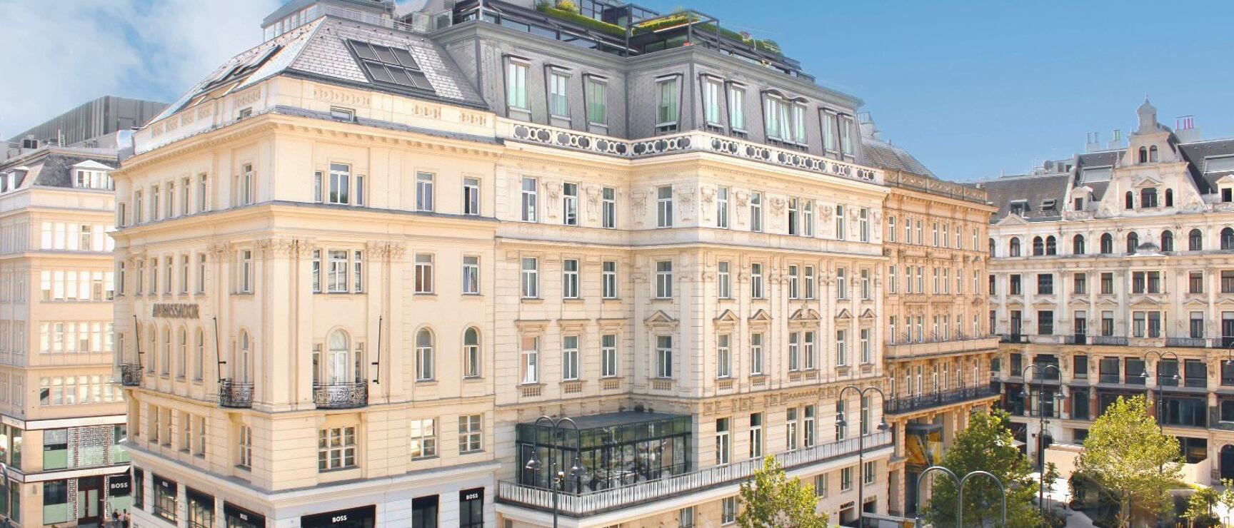 Gründerzeitfassade des Hotel Ambassador an der Kärntner Straße in Wien, Fußgänger und Geschäfte im Erdgeschoss.
