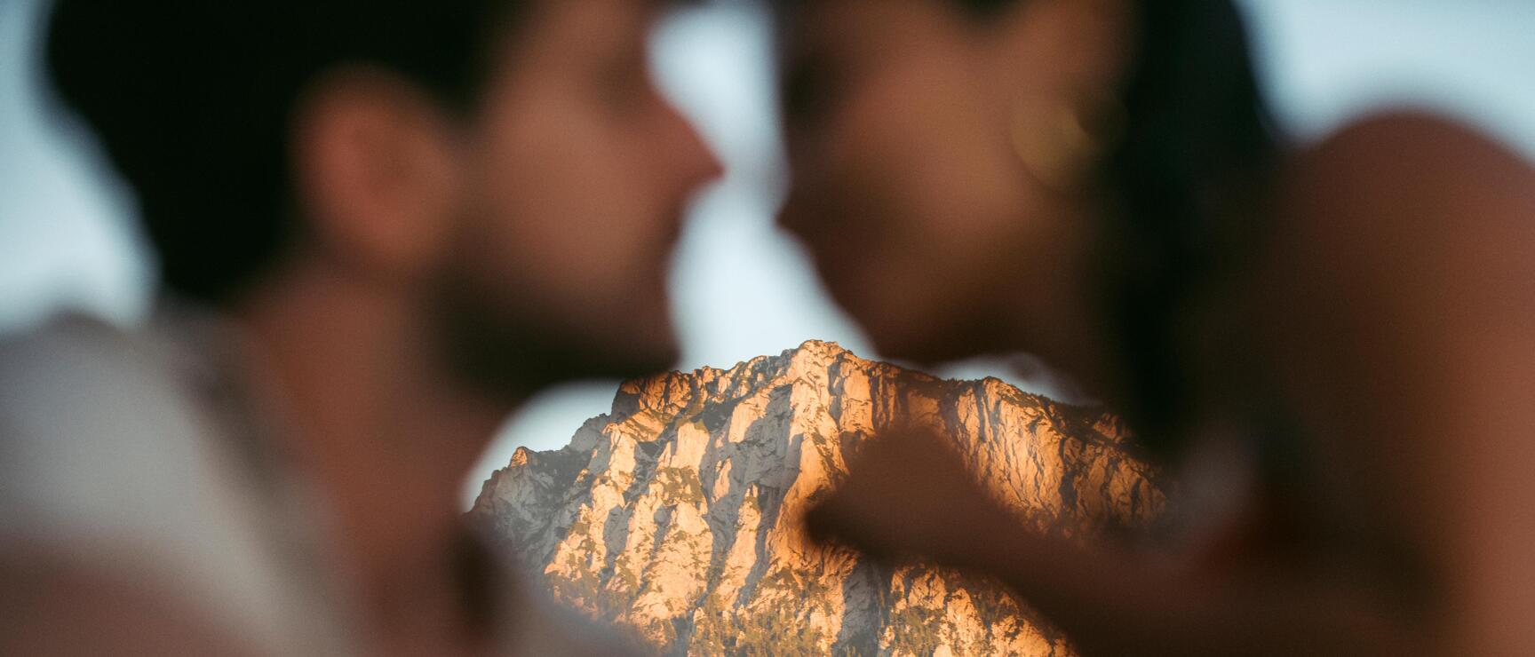 Zwei Personen im Vordergrund unscharf, dahinter Felsgipfel im Abendlicht.