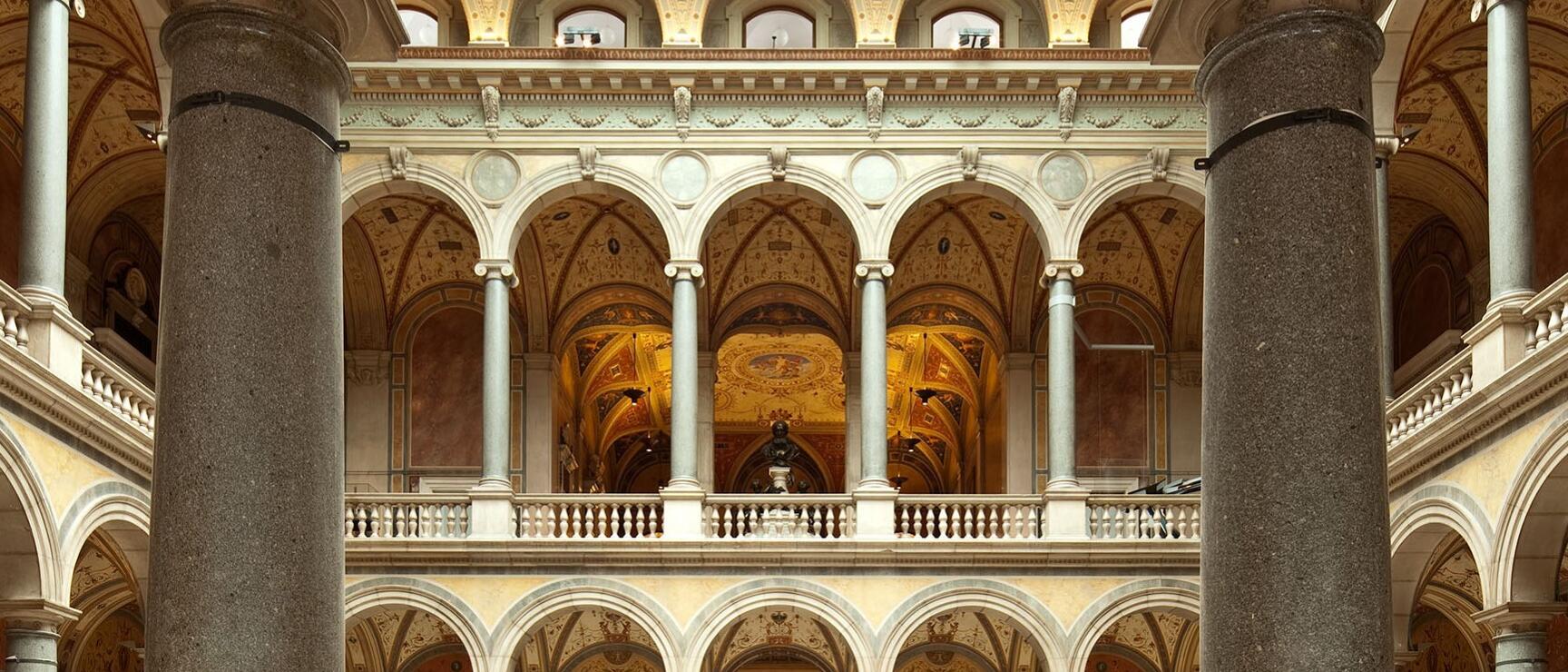Splendid interior courtyard of the Museum of Art History Vienna with columns, arcades and gilded ceiling paintings.