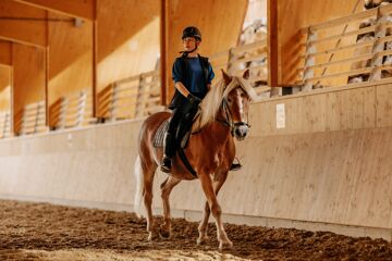 Woman riding in the indoor riding arena