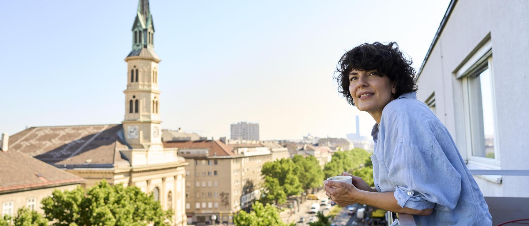 Woman standing on the balcony of the city hotel Henriette Vienna