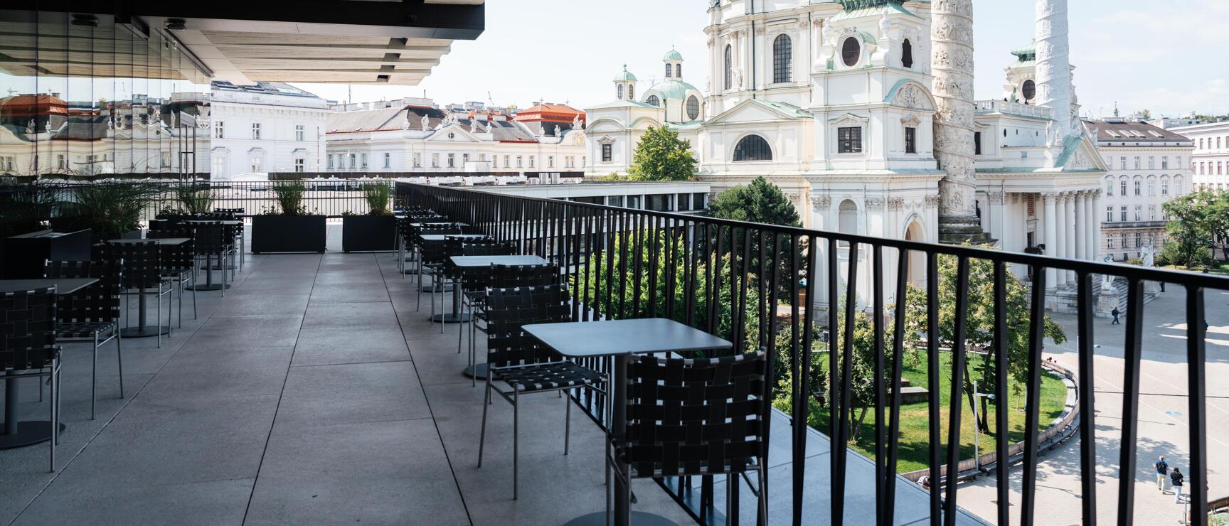 Empty terrace with tables and chairs overlooking Karlskirche with green dome, Vienna