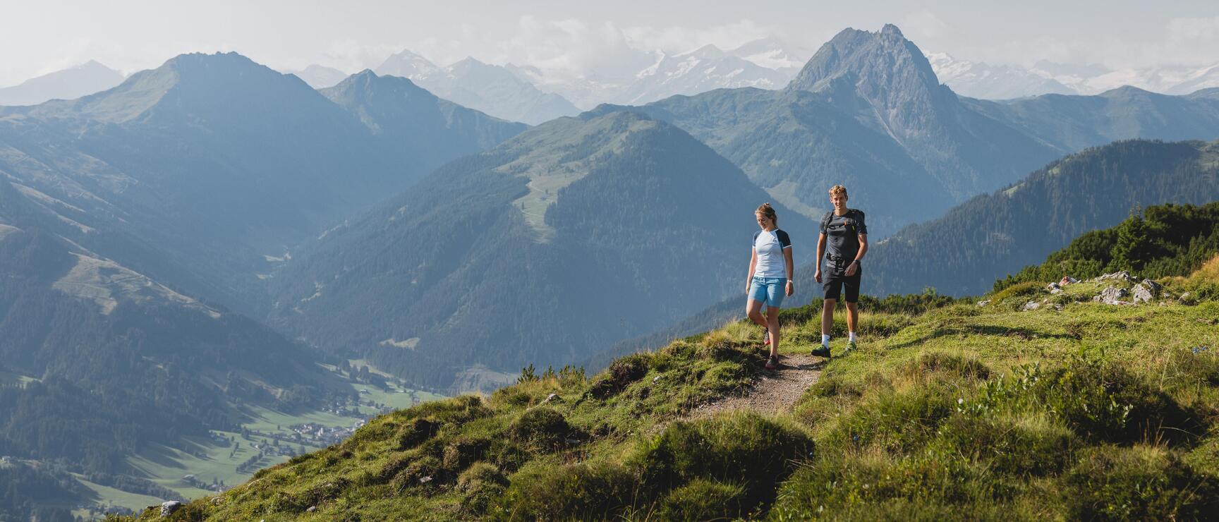 A couple hiking on the gentle grassy mountains in the Brixental valley