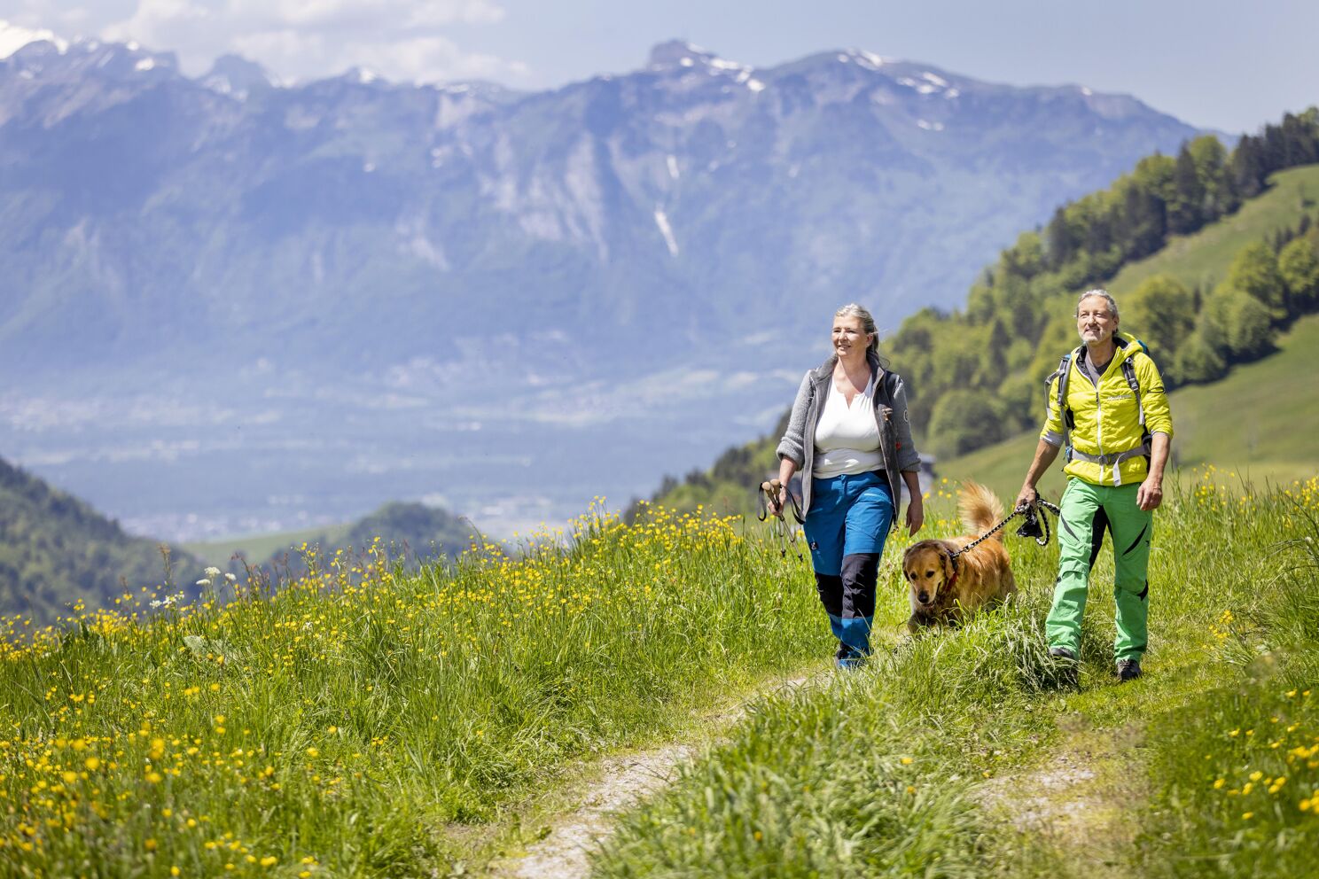 Ihr seht ein Ehepaar beim Wandern mit ihren Hund im Laternsertal in der Nähe des JUFA Hotel Laterns***.